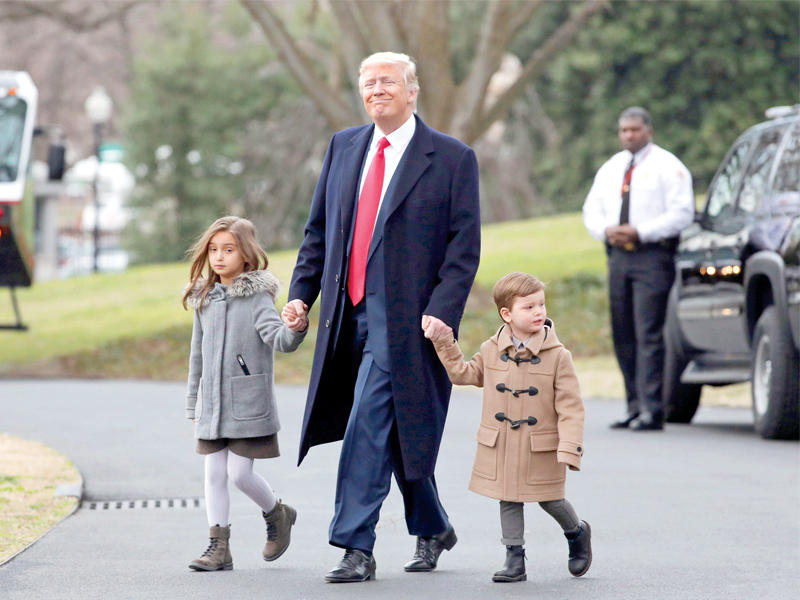 ترامب مع حفيديه قبيل الصعود إلى مروحية «مارين وان» الرئاسية في واشنطن أمس   (رويترز)n