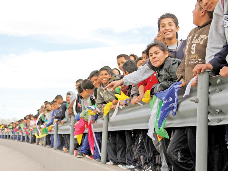 طلاب مكسيكيون يشكلون سلسلة بشرية اعتراضاً على جدار ترامب الحدودي في بلدة سيوداد خواريز أمس (رويترز)