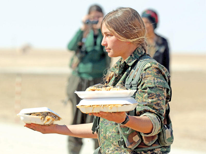 مقاتلة كردية تحمل طعاماً لزملائها في جبهة قرية صباح الخير على مشارف مدينة دير الزور أمس الأول (أ ف ب)