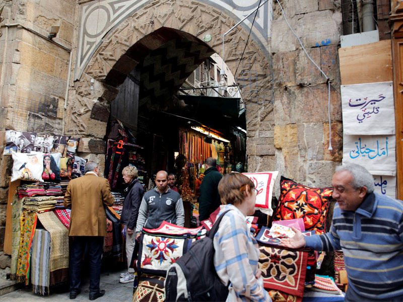 بائع يعرض هدايا تذكارية على سائحة بشارع خان الخليلي قرب حي الأزهر جنوب القاهرة أمس     (رويترز)