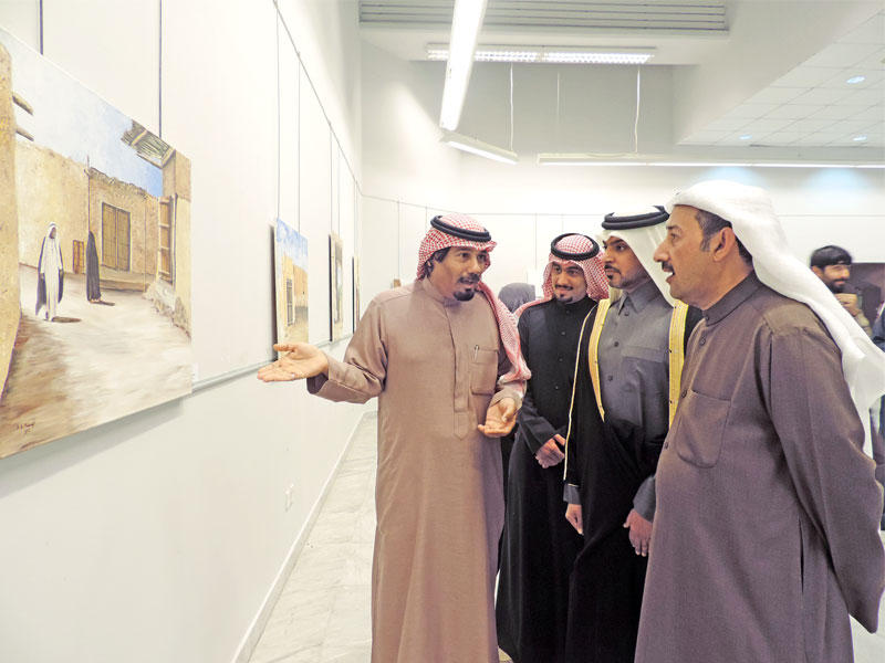 العسعوسي والقحطاني يستمعان إلى شرح أحد الفنانين المشاركين في المعرض 