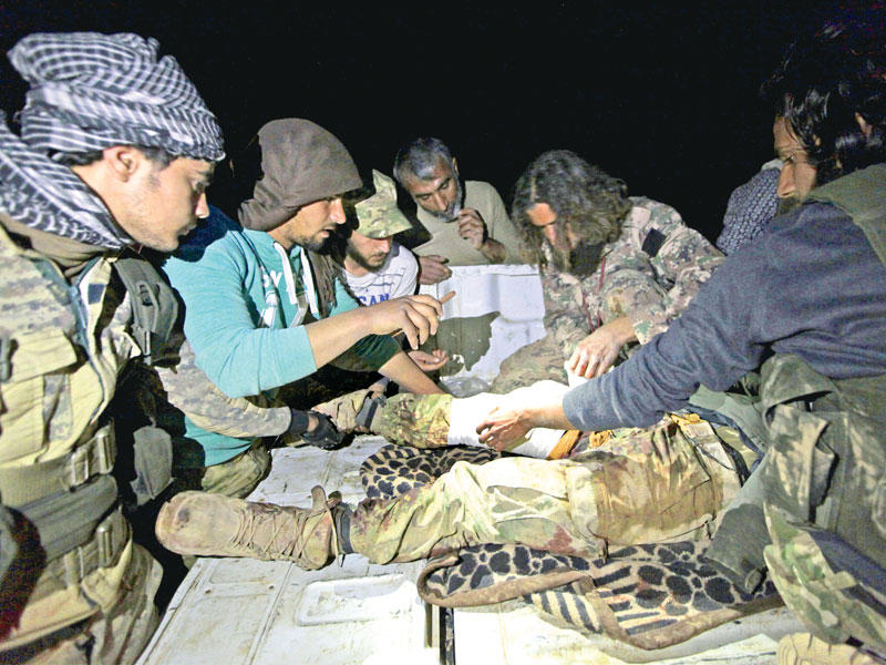 مصاب من الجيش الحر يتلقى العلاج على أضواء الهواتف شرق الباب أمس الأول    (رويترز)