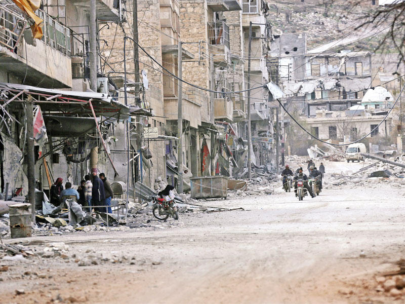 سوريون يتجولون بالدراجات النارية وسط أنقاض مدينة الباب أمس الأولt(رويترز)