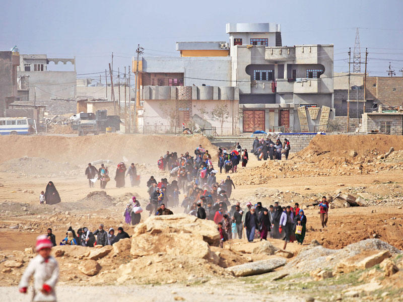 مدنيون عراقيون يفرون من مجمع شقق المأمون في غرب الموصل أمس (رويترز)