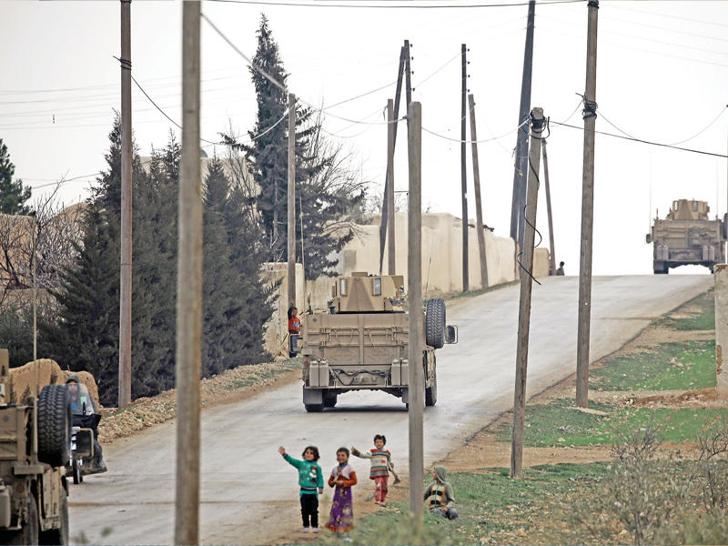 أطفال سوريون يحيون قافلة أميركية وصلت إلى منبج أمس الأول  (أ ف ب)