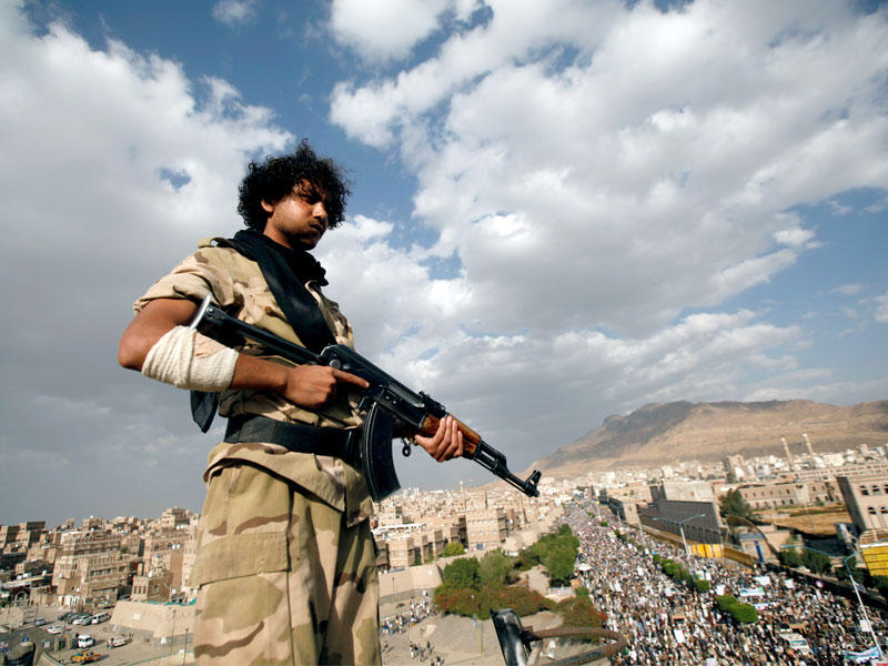 حوثي يقف حارسا على سطح مبنى يطل على تظاهرة شارك فيها أنصار حركة الحوثي في صنعاء