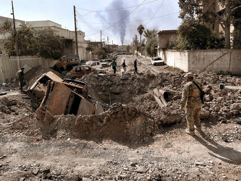 أحد أفراد القوات العراقية ينظر إلى فوهة بعد غارة جوية في غرب الموصل مع استمرار القوات العراقية القتال ضد داعش