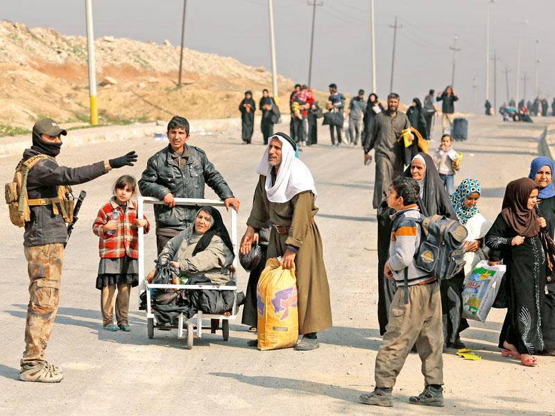 عراقيون يسألون جندياً إرشادهم إلى أقرب مخيم للنازحين في الموصل أمس (رويترز)