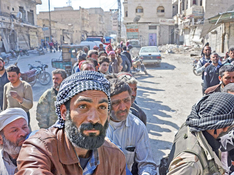 سوريون يصطفون للحصول على مساعدات غذائية بمدينة الباب أمس الأول  (أ ف ب)