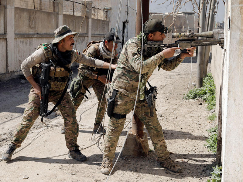 جنديان عراقيان يساعدان زميلهما القناص لمعرفة مكان قناص داعشي في أحد أحياء وسط الموصل أمس (رويترز)