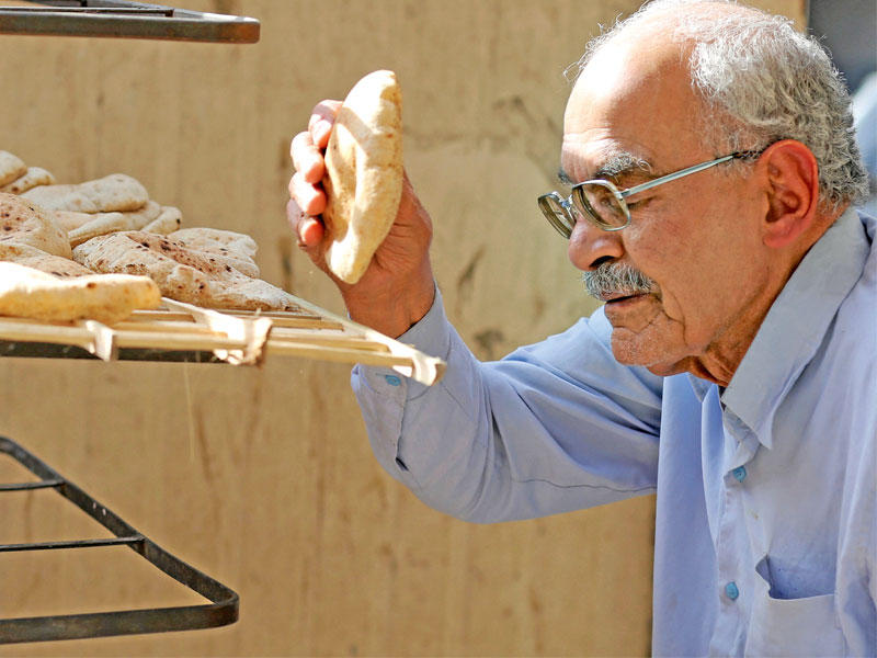 مسن مصري يشتري الخبز من نقطة بيع في القاهرة أمس الأول (رويترز)