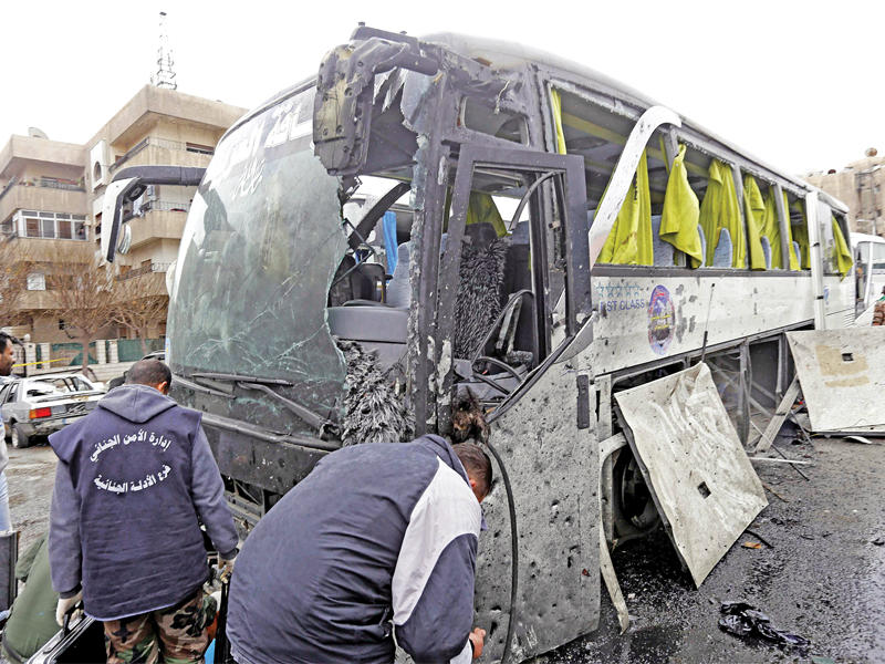 عناصر من الأدلة الجنائية يفحصون حافلة مدمرة في باب الصغير أمس  (أ ف ب)