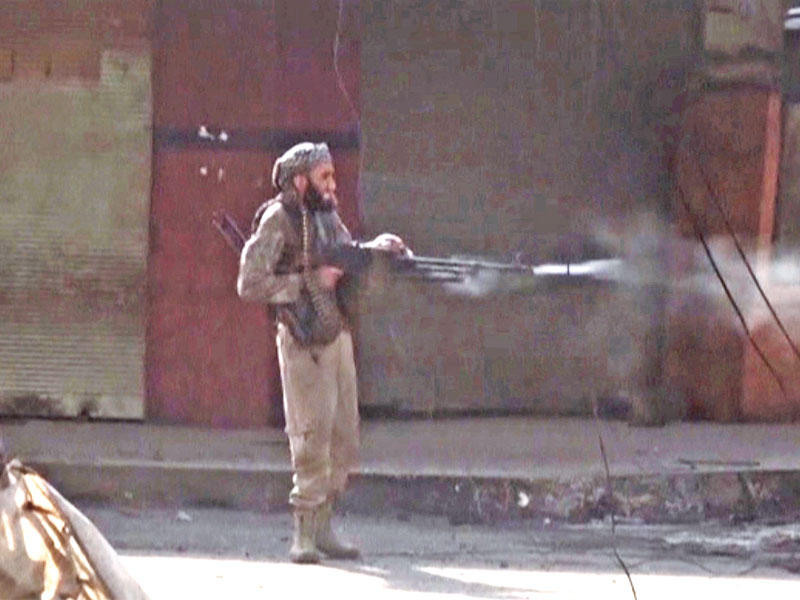 أحد عناصر «داعش» يطلق النار في اتجاه القوات العراقية في الموصل أمس (رويترز)