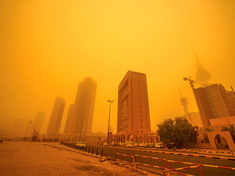 الغبار الكثيف يحجب مباني العاصمة أمس وفي الإطار «كمامات» لمواجهته (تصوير رائد قطينة)