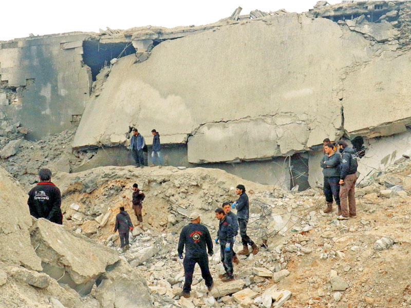 سوريون على أنقاض مسجد قرية الجينة أمس (رويترز)