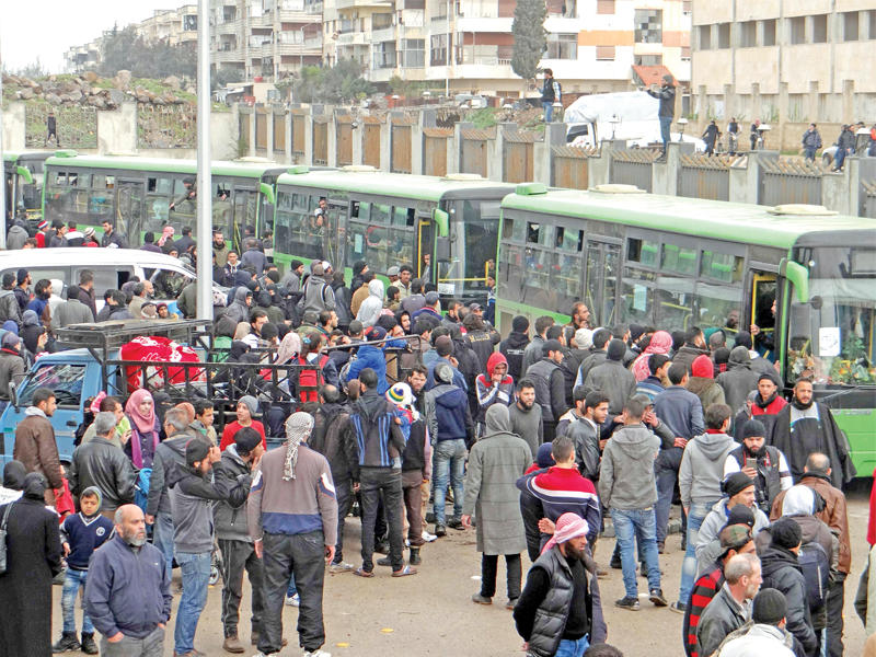 مئات المقاتلين السوريين يخرجون من حي الوعر أمس (أ ف ب)