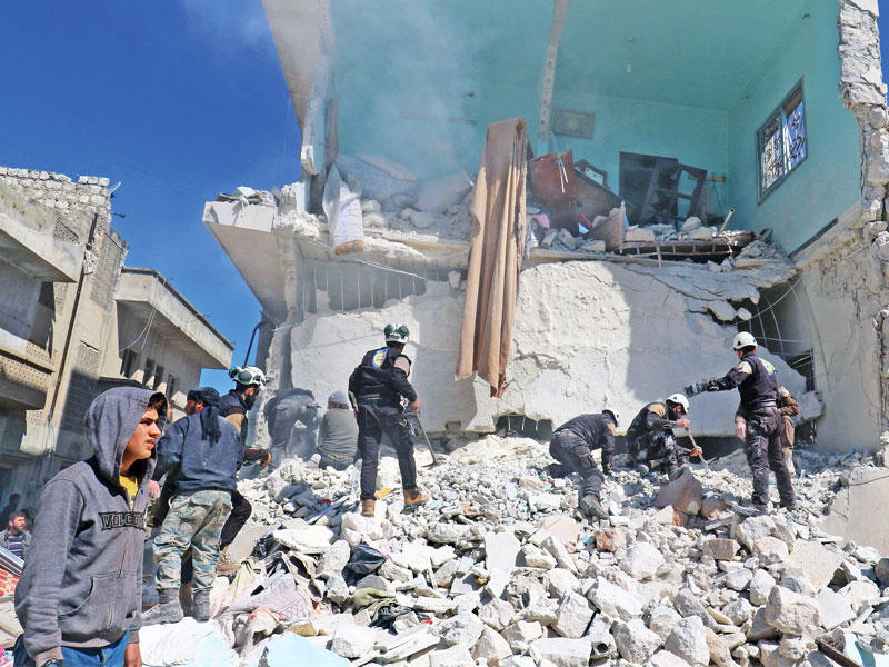 سوريون يبحثون عن ناجين تحت أنقاض مبنى دمرته غارة جوية على مدينة إدلب أمس    (رويترز)