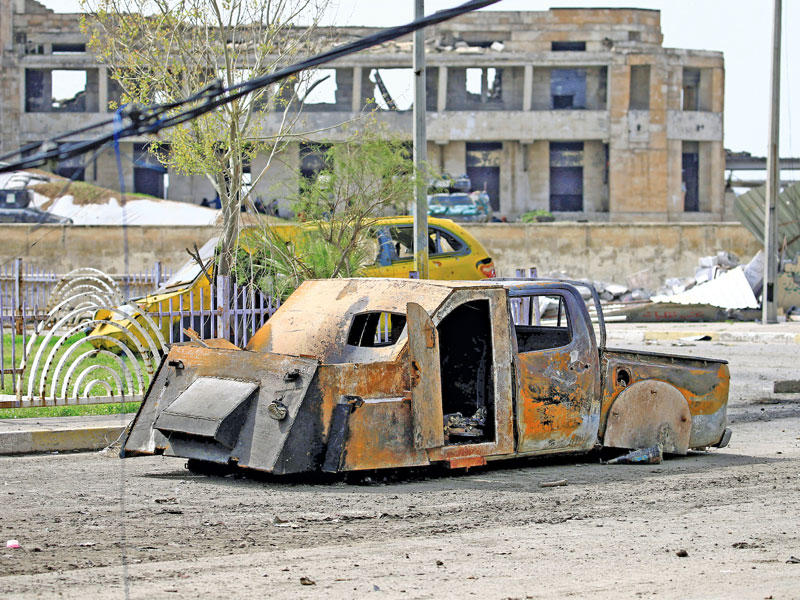 سيارة تابعة لتنظيم «داعش» محترقة جراء قصف القوات العراقية متوقفة في أحد شوارع الموصل أمس (رويترز) 