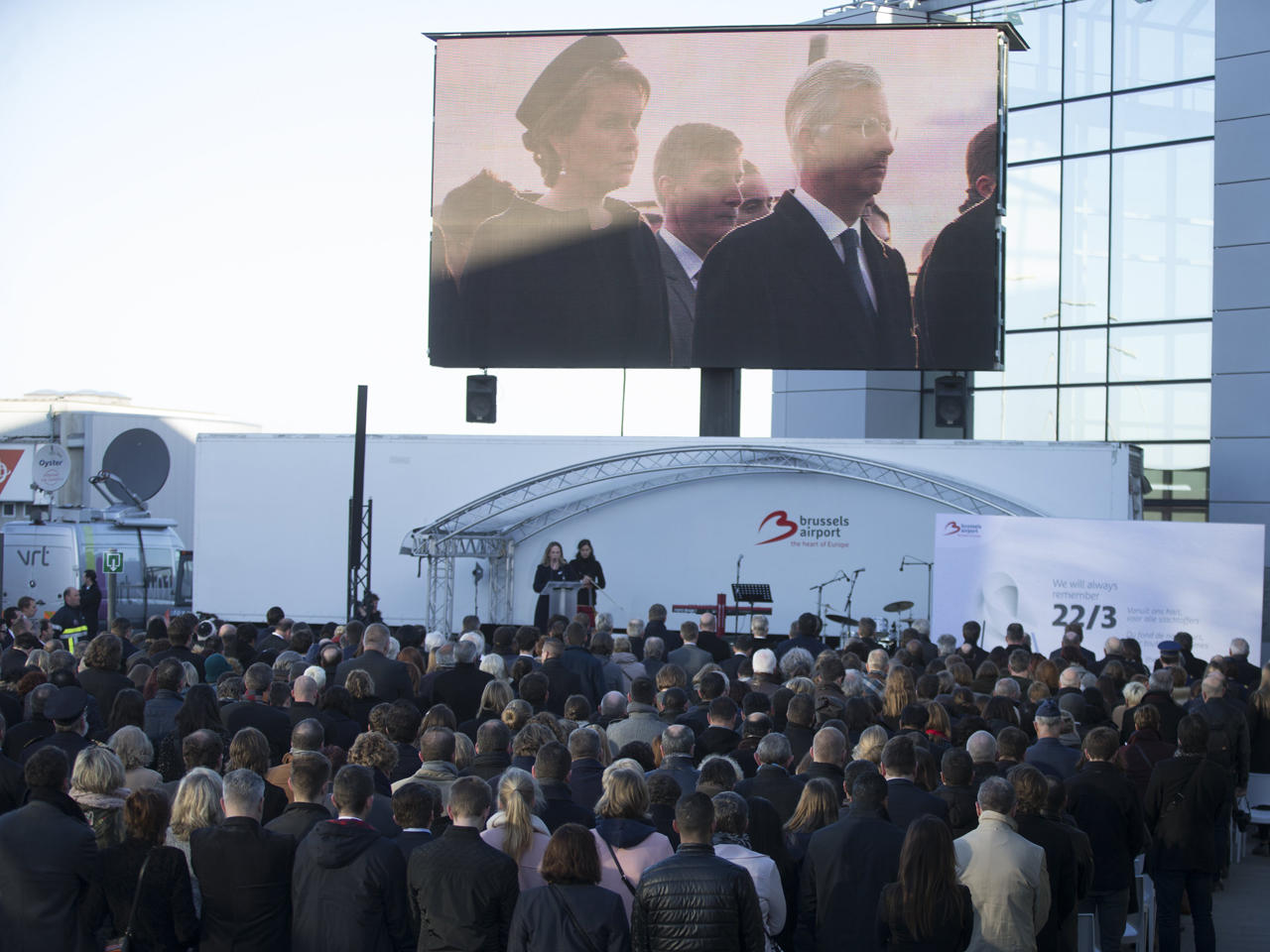 الملكة ماتيلد والملك فيليب على شاشة عملاقة أثناء حضورهما احتفالاً تذكارياً بمناسبة الذكرى السنوية الأولى لهجمات بروكسل الإرهابية في ببلجيكا