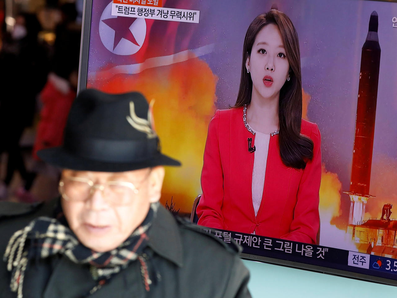 رجل يمر عبر شاشة تلفزيون يبث تقريراً إخبارياً عن إطلاق كوريا الشمالية لصاروخاً باليستياً على البحر قبالة ساحلها الشرقي، في محطة للسكك الحديدية في سيول، كوريا الجنوبية.