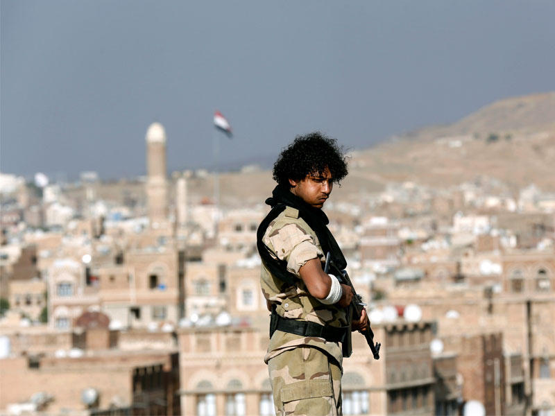 ارشيفية مسلح حوثي يقف حارسا على سطح مبنى يطل على تجمع يحضره أنصار حركة الحوثيين في صنعاء