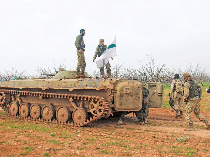 مقاتلو هيئة تحرير الشام على مدرعة تحمل رايتها قرب معردس في ريف حماة السورية أمس الأول     (أ ف ب)