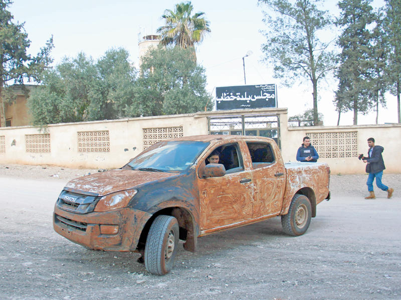 مقاتلو المعارضة أمام مبنى المجلس المحلي لقرية رحبة خطاب بمحافظة حماة أمس الأول (أ ف ب)