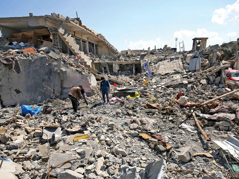 عراقيون في الموقع الذي شهد مجزرة بحي الموصل الجديدة اليوم (أ ف ب)