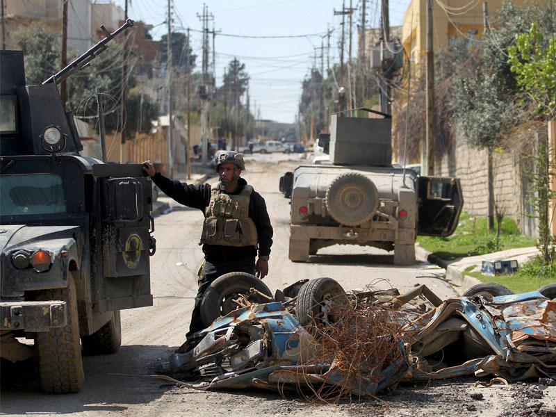 أحد أفراد القوات العراقية بالقرب من سيارة مفخخة في منطقة الموصل الجديدة