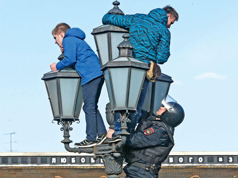 شرطي روسي من قوات مكافحة الشغب يطارد متظاهرين في موسكو أمس الأول  ( اي بي ايه)