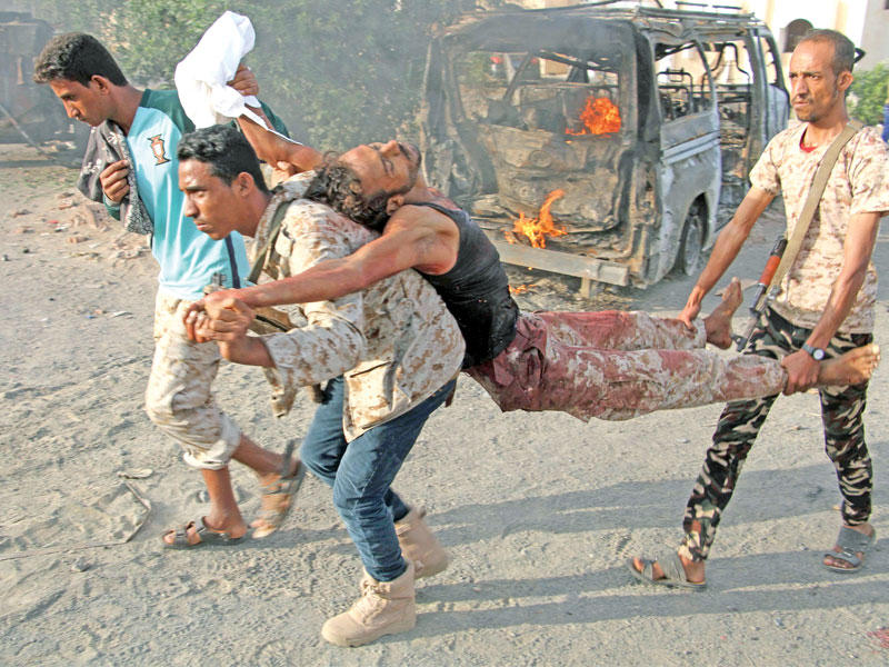 يمنيون يحملون مصاباً في هجوم لتنظيم «القاعدة» استهدف القوات الحكومية بمحافظة لحج اليوم الأول (أ ف ب)