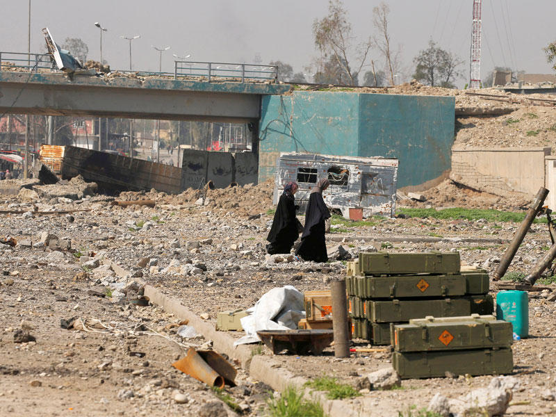 عراقيتان تمران أمام مدافع هاون وذخائر في أحد أحياء غرب الموصل أمسt(رويترز)