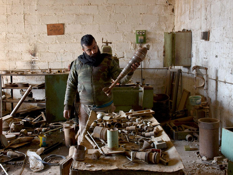 جندي نظامي يتفقد قذائف محلية الصنع بمبنى في دير حافر أمس (أ ف ب)