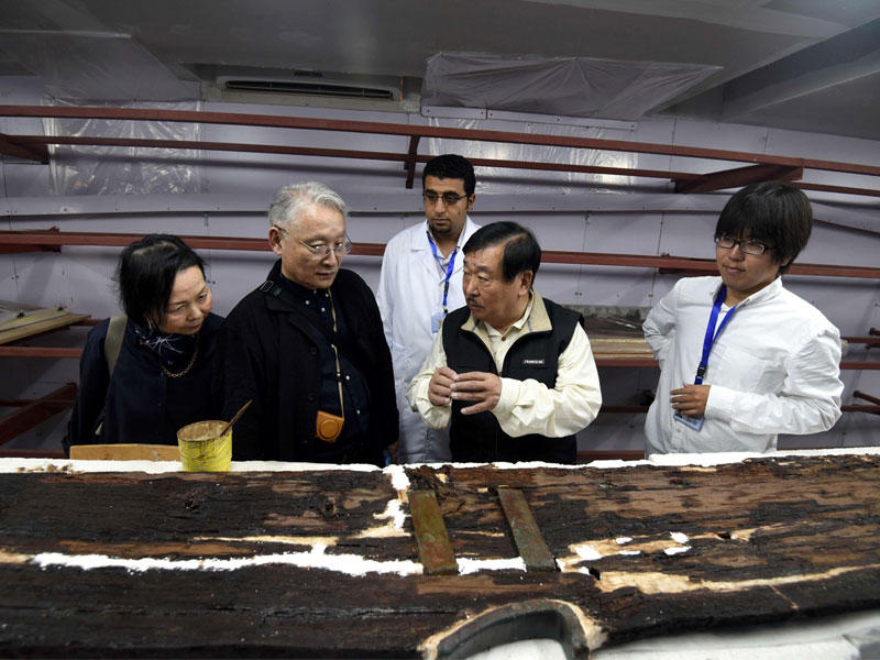 علماء آثار يابانيون يفحصون قطعة خشبية من قارب خوفو الثاني الذي يخضع لعملية ترميم في مختبر بمحافظة الجيزة شمال القاهرة أمس الأول (أ ف ب)