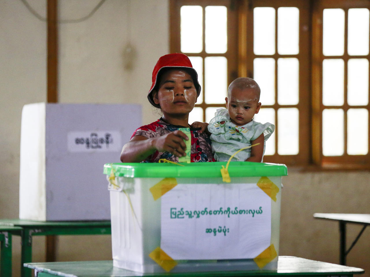 امرأة تحمل طفلها وتدلي بصوتها في الانتخابات الفرعية بمركز اقتراع من بلدة هلاينغ ثار يار في يانغون