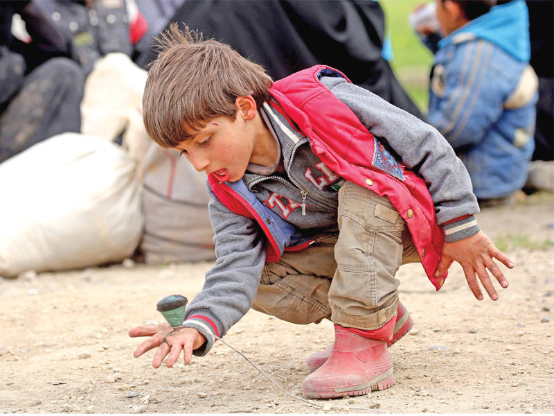 صبي فار مع عائلته من الرقة يلعب الدوامة في مخيم مؤقت بقرية عين عيسى أمس الأول (أ ف ب)