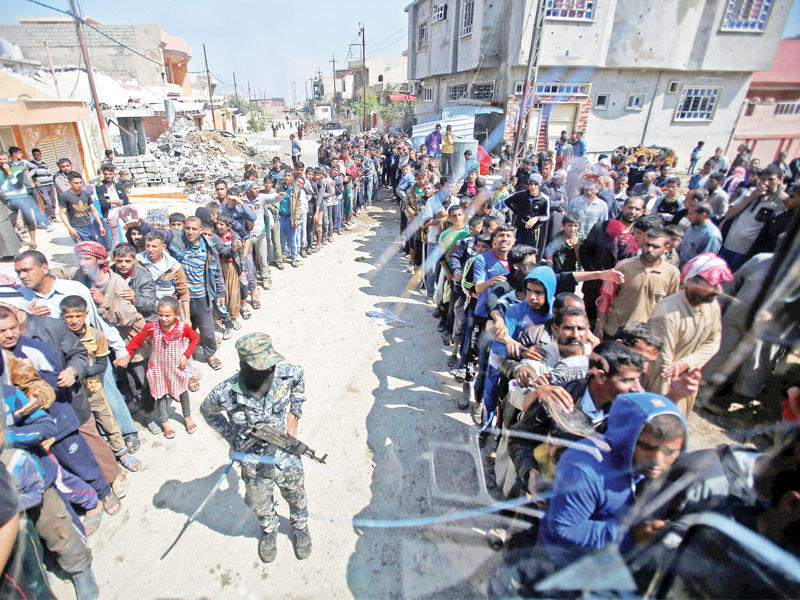 عراقيون يتلقون مساعدات في الجانب المحرر من الموصل اليوم (رويترز) 