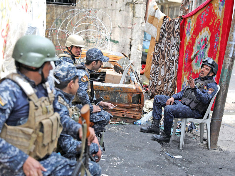 عناصر من الشرطة الاتحادية في أحد أزقة الموصل أمس، وقد نصبوا بطانيات لمنع القناصة من استهدافهم (رويترز)