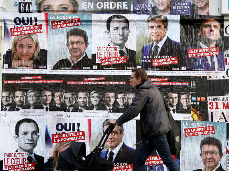 رجل  يمشي بجانب ملصقات الحملات الانتخابية الفرنسية 2017