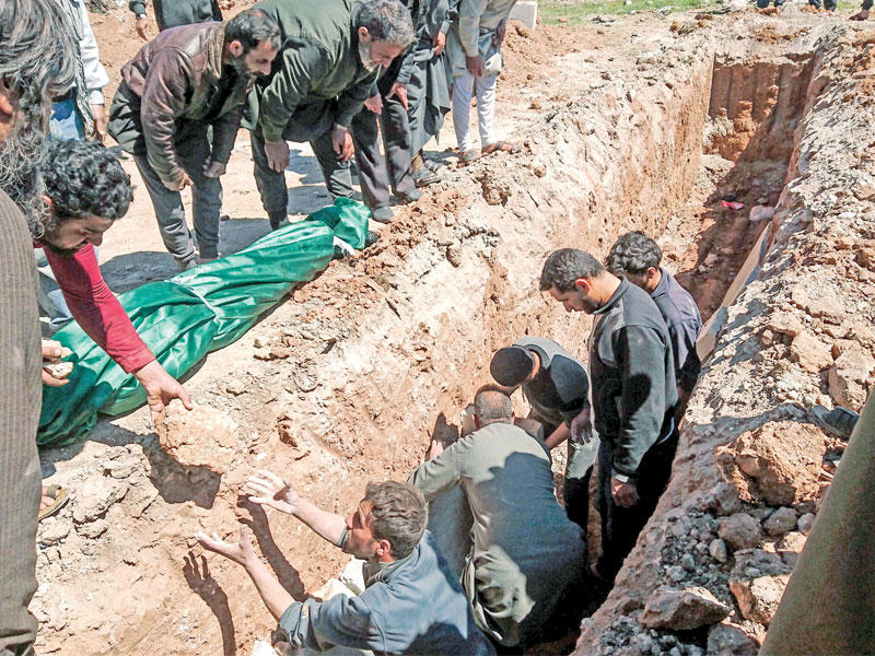 سوريون يوارون أحد ضحايا الهجوم الكيماوي في مقبرة جماعية بخان شيخون أمس (أ ف ب)