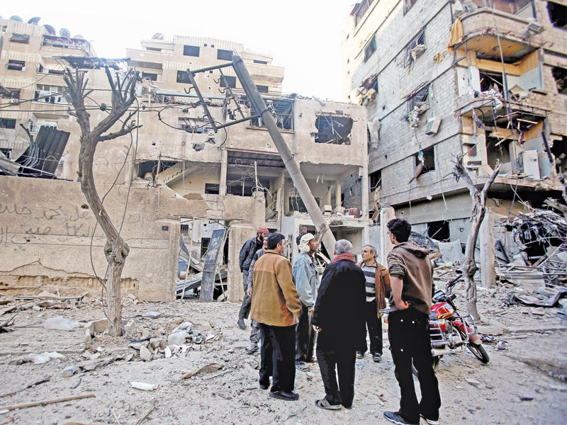 سوريون يتفقدون موقع غارة نظامية على دوما أمس (إي بي إيه)