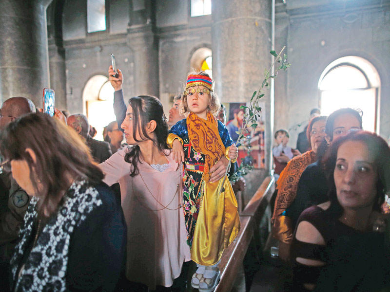 عراقيون يحيون أحد السعف داخل كنيسة قرقوش المحترقة أمسt(أ ف ب)