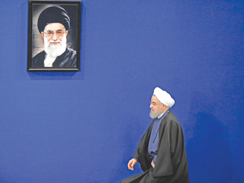 روحاني يمر تحت صورة كبيرة للمرشد الأعلى علي خامنئي قبيل مؤتمر صحافي  في طهران اليوم (أي بي أيه)