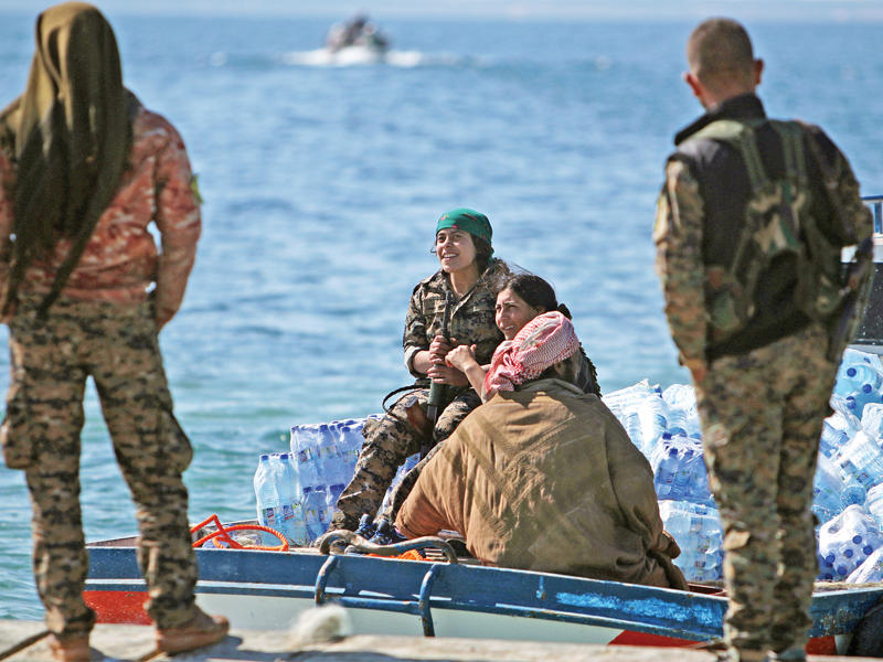 إمدادات لقوات سورية الديمقراطية تصل عبر قارب إلى الضفة الغربية لنهر الفرات قرب الرقة أمس (رويترز)