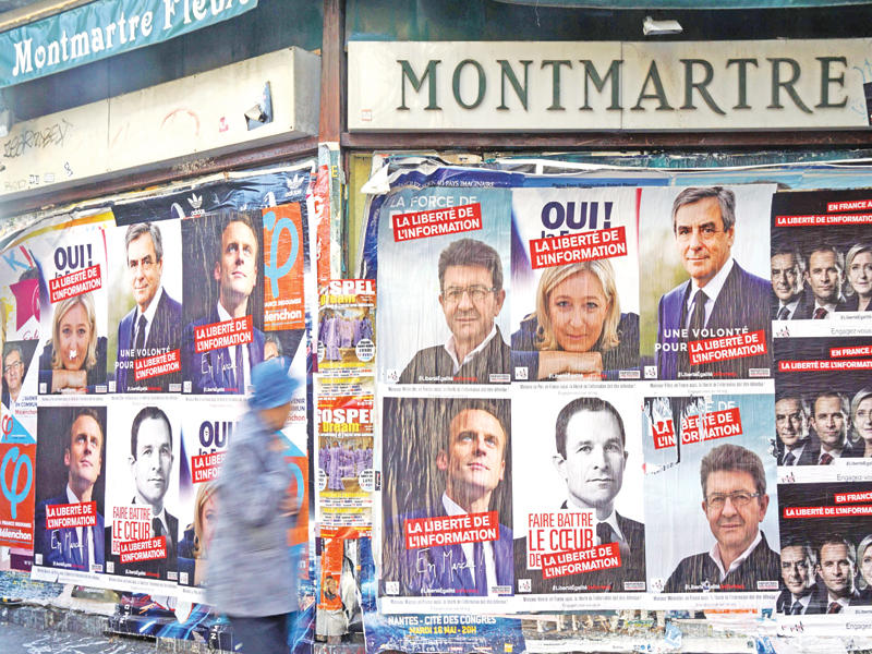 صور المرشحين الرئاسيين على جدار في حي مونتمارتر بباريس (أ ف ب)