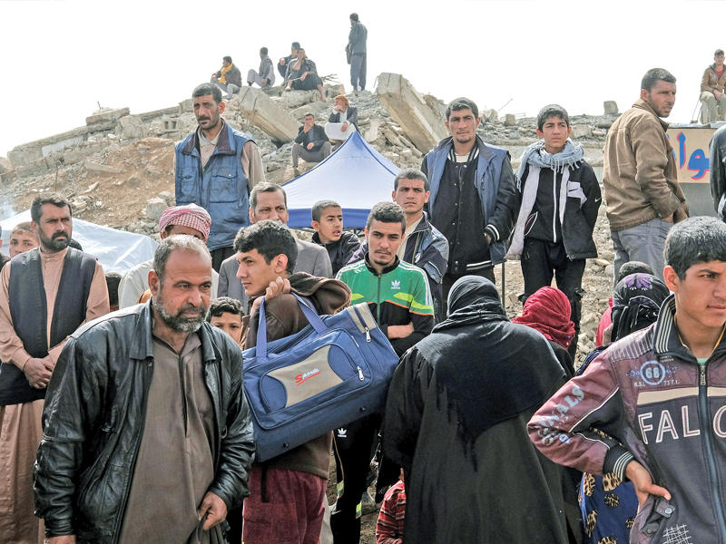 نازحون من أيمن الموصل ينتظرون السماح لهم بالدخول لمخيم حمام العليل اليوم (رويترز)