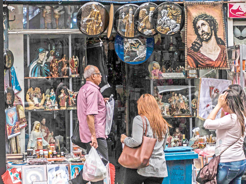 أقباط أمام محل لبيع الرموز والكتب الدينية المسيحية بحي شبرا شمال القاهرة أمس (أ ف ب)