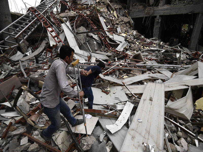 عراقيان أحدهما مصاب يسيران وسط ركام جامعة الموصل أمس       (أ ف ب)