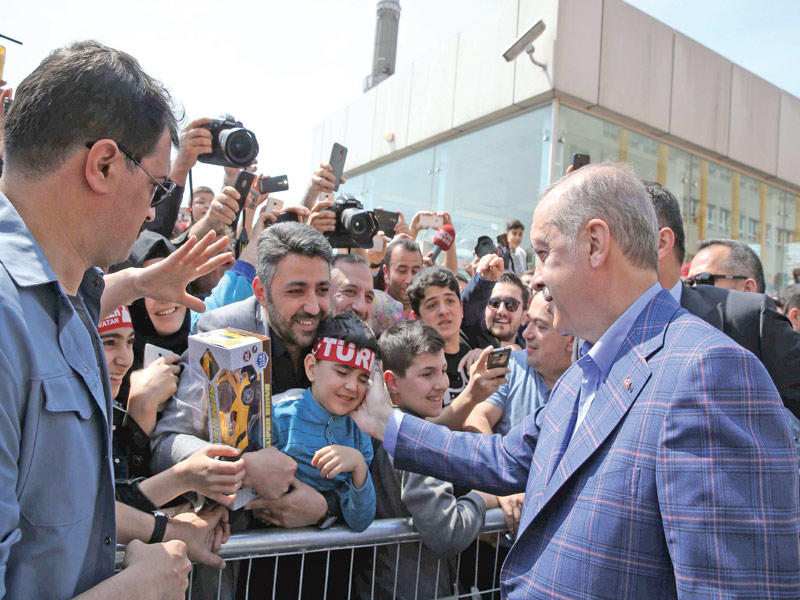 إردوغان يداعب طفل أحد أنصاره خارج مركز الاقتراع في إسطنبول أمس   (رويترز)