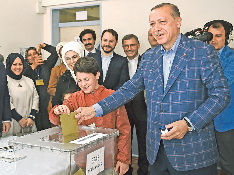 إردوغان يدلي بصوته داخل لجنة بصحبة عقيلته وأحد أحفاده في إسطنبول أمس (أ ف ب)